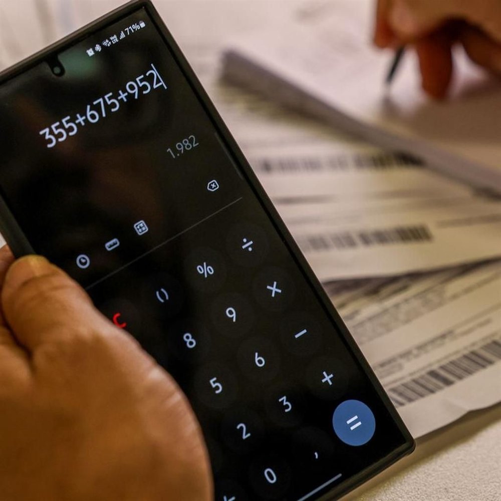 Pequeno empresário organizando as finanças do negócio na calculadora